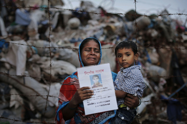 A woman holds a picture of her son, a garment worker who went missing following the collapse of the Rana Plaza building in Savar, Dhaka, Bangladesh, June 14.   AP-Yonhap News