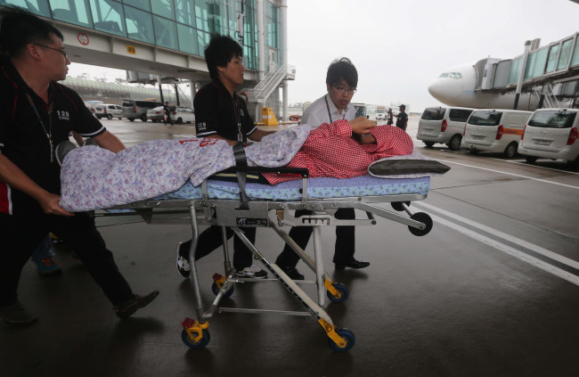 Airport staff transfer a Korean passenger who survived Asiana Airlines flight 214, which crash-landed at San Francisco Airport this weekend, to a hospital upon arrival at Incheon International Airport on Monday.   Kim Myung-sub/The Korea Herald