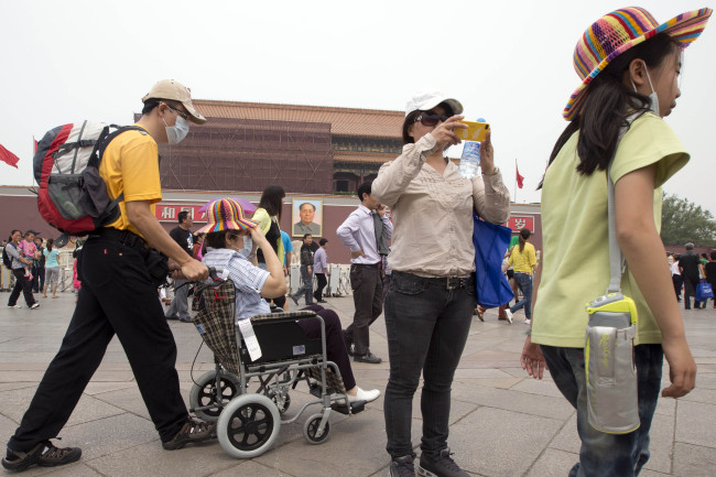 Visitors to Tiananmen Gate wear masks during a day of heavy pollution in Beijing on May 7.   AP-Yonhap News