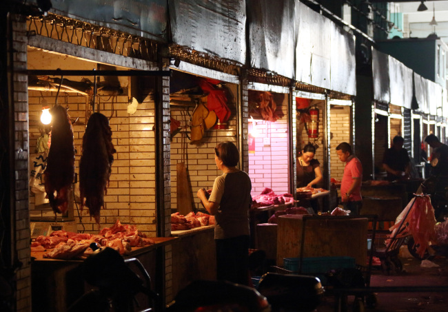 Customers shop for cuts of pork at a wholesale market in Shanghai.   Bloomberg