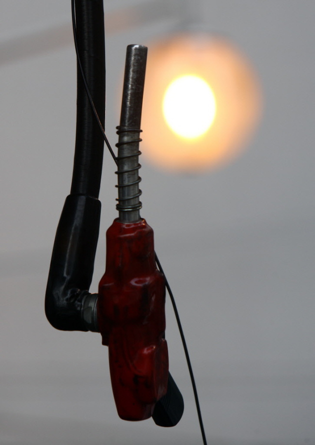 A fuel nozzle gun hangs at a gas station in Tokyo.   Bloomberg