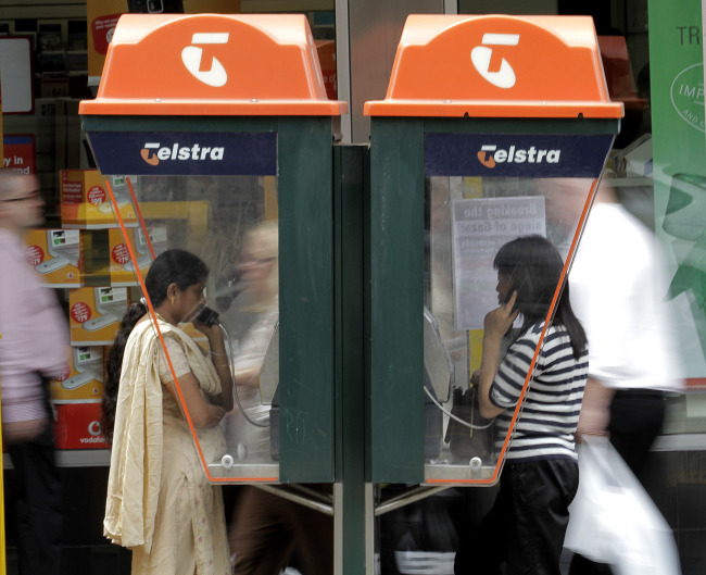 People talk on Telstra Corp. pay phones in Melbourne, Australia.   Bloomberg
