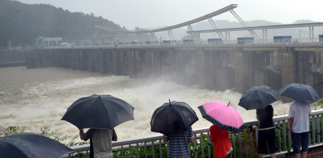 People watch the opened floodgates of Paldang Dam in Hanam, Gyeonggi Province, Sunday. ( Kim Myung-sub/ The Korea Herald)