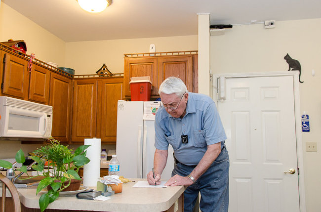 In this May 22, photo provided by the University of Missouri, Bob Harrison writes in his TigerPlace apartment in Columbia, Missouri, as different sensors mounted near the ceiling record activity patterns.   AP-Yonhap News