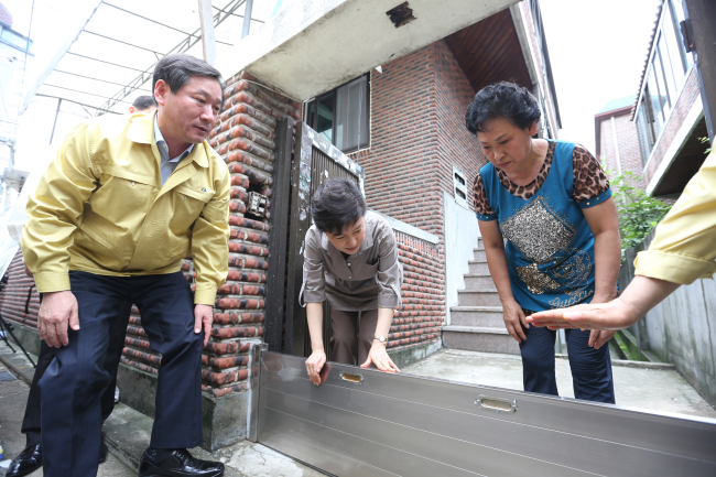 President Park Geun-hye inspects a water barrier installed at a home in western Seoul in an area commonly affected by floods on Monday accompanied by Minister of Security and Public Administration Yoo Jeong-bok (left).   Cheong Wa Dae Joint Press Corps