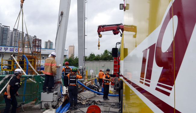Rescuers work at a reservoir construction site in Seoul on Tuesday after an accident that killed one worker and left six others missing Monday.   Ahn Hoon/The Korea Herald