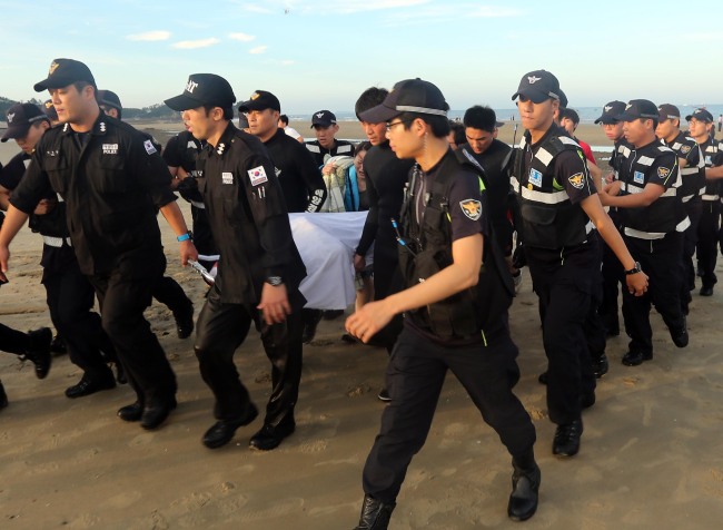 Taean Coast Guard officials carry the body of a high school student found dead near Baeksajang Beach in Taean, South Chungcheong Province, Friday.   Yonhap News