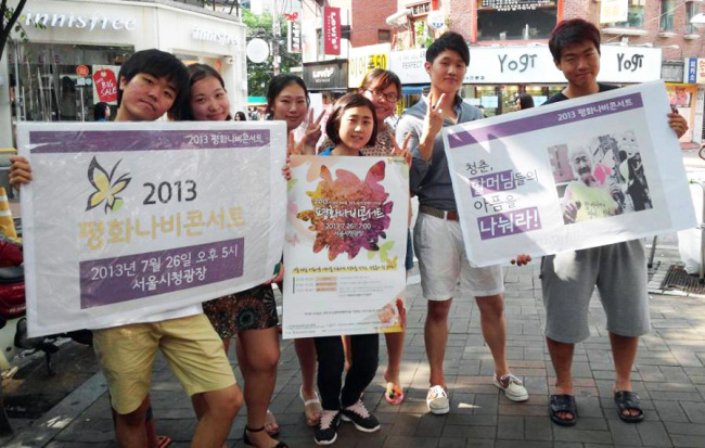 <YONHAP PHOTO-0257> "26일 서울광장 평화나비콘서트에서 만나요" (서울=연합뉴스) 김수진 기자 = 19일 오후 서울 지하철2호선 홍대입구역 인근 걷고싶은 거리에서 평화나비 콘서트 기획단 학생들이 홍보 피켓을 들고 활짝 웃고 있다. 2013.07.21 gogogo@yna.co.kr/2013-07-21 07:54:40/ <저작권자 ⓒ 1980-2013 ㈜연합뉴스. 무단 전재 재배포 금지.>
Students promote a concert for former comfort women near Hongik University, Seoul, Friday.   Yonhap News