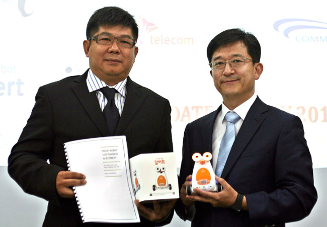 SK Telecom smart learning business chief Kim Don-jung (right) poses with CommBax chief K. C. Tan after signing an agreement on its exports of robots to the Malaysian firm in Kuala Lumpur on Monday.   SKT