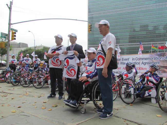 Korean veterans with paralysis, along with New York Consul General Son Se-joo (second from left, front row) and other officials hold a ceremony before the start of a 600-km handcycle journey in front of the U.N. headquarters in New York on Monday.   Yonhap News