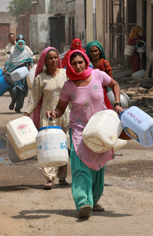 Residents carry plastic containers to collect water from a government water supply tank in New Delhi.   Bloomberg