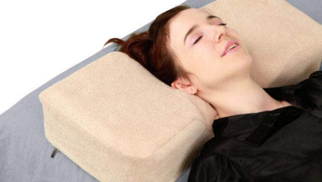 A woman rests on a KANUDA pillow.   T&I