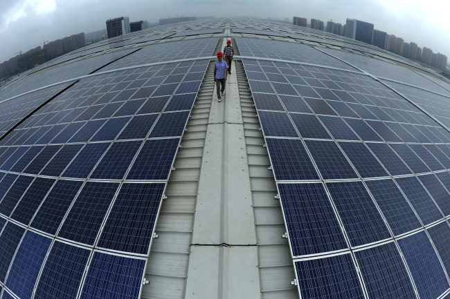 Two men walk on the roof of Hangzhou East Railway Station, which is covered by solar panels.   AP-Yonhap News