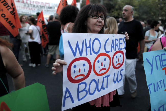 A protesting civil servant holds a banner during a rally in central Syntagma Square outside the Greek Parliament in Athens on July 15.    AP-Yonhap News