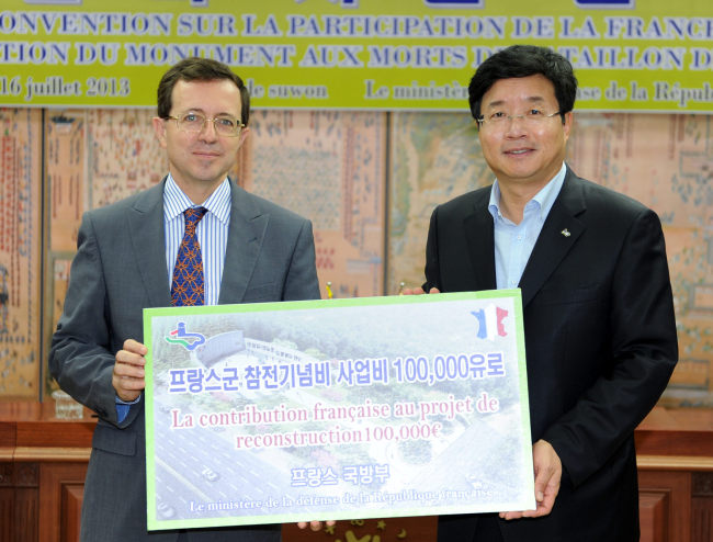 French Ambassador to Korea Jerome Pasquier and Suwon Mayor Yeom Taeyoung hold up a placard denoting 100,000 euros that France has committed to refurbishing the war memorial. (Yonhap News)