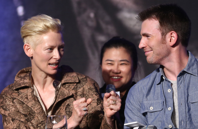 Tilda Swinton (left) and Chris Evans look at each other during a press conference to promote their sci-fi thriller “Snowpiercer” in Seoul on Monday.   Yonhap News