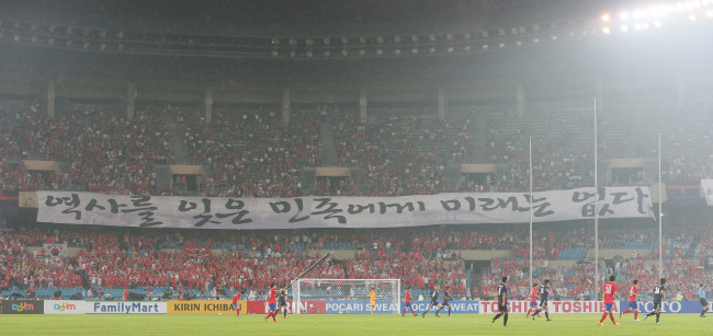 The Red Devils put up an anti-Japan banner during the soccer match between Korea and Japan at the East Asian Cup finals in Seoul on Sunday.   Yonhap News