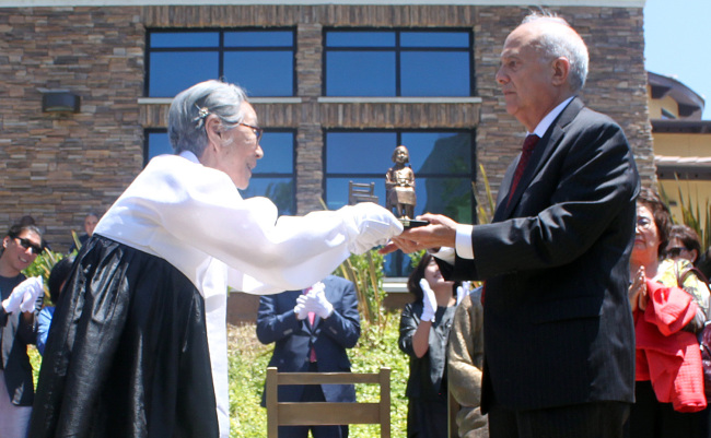 Kim Bok-dong (left), a former Korean comfort woman, receives a miniature replica of the comfort woman statue from Glendale Councilman Frank Quintero in the unveiling ceremony for the monument in front of the Glendale Central Library in Glendale, California, Tuesday.   Yonhap News