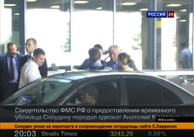 This still image shows Russian lawyer Anatoly Kucherena (center, second from right) and National Security Agency leaker Edward Snowden (center, back to camera), as Snowden leaves Sheremetyevo airport outside Moscow on Thursday.   AP-Yonhap News