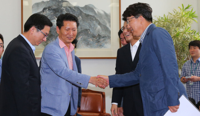Rep. Jung Cheong-rae (second from left) of the Democratic Party and Rep. Kweon Sung-dong (right) of the Saenuri Party shake hands at a meeting on the parliamentary investigation into the National Intelligence Service at the National Assembly on Sunday.   Yonhap News