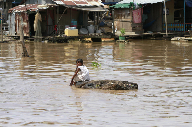 A girl uses a log to cross the Mekong River while heading to her floating house during the flood season in Arey Ksat village on the outskirts of Phnom Penh, Cambodia, Sunday.   AP-Yonhap News