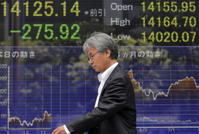A man walks by an electronic stock board in Tokyo on Wednesday.     AP-Yonhap News