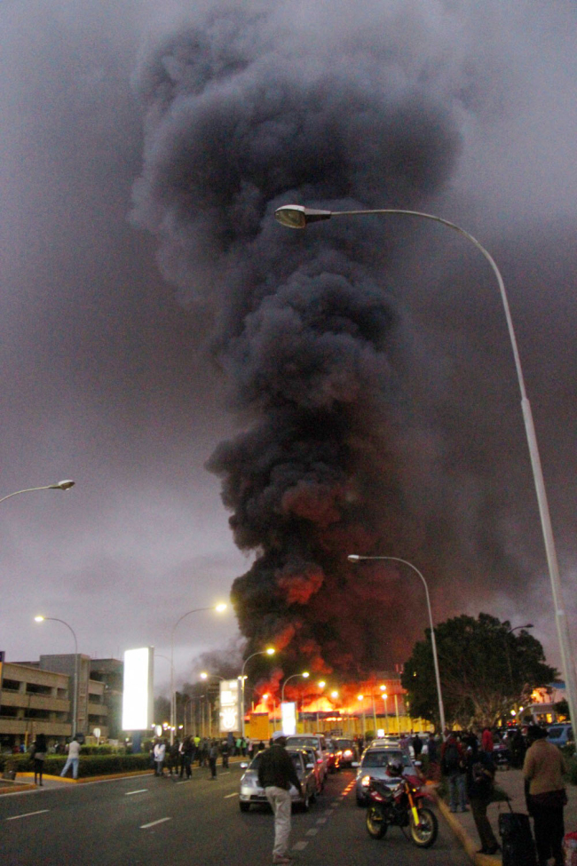 People watch black smoke billowing from the Jomo Kenyatta International Airport in Nairobi on Wednesday.   AP-Yonhap News