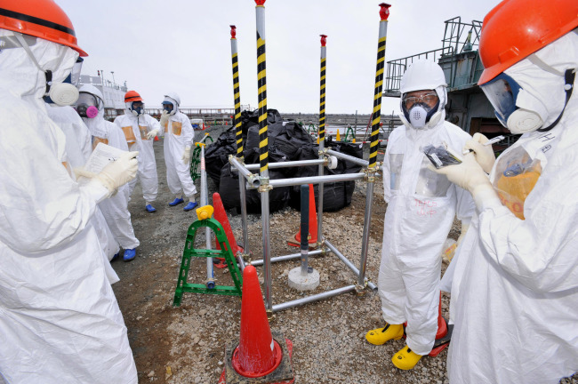 Reporters inspect an observation well which is dug to take underground water samples near Fukushima Dai-ichi nuclear plant Unit 1 of Tokyo Electric Power Co., in Okuma, Fukushima prefecture, northeastern Japan.   AP-Yonhap News