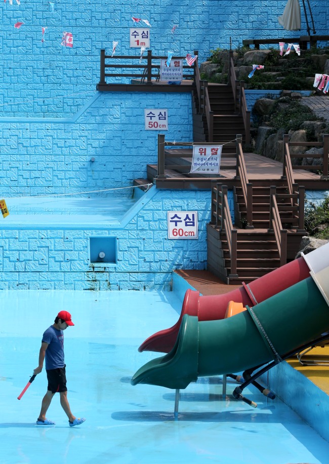 A lifeguard walks across a swimming pool that has dried up due to the prolonged drought in Naju, South Jeolla Province, Thursday.   Yonhap News