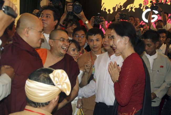 Myanmar opposition leader Aung San Suu Kyi (right) meets Buddhist monks during the 25th anniversary of Myanmar’s pro-democracy uprising at Myanmar Convention Center in Yangon on Thursday.   AP-Yonhap News