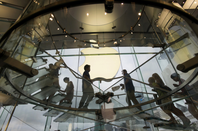 Customers walk up and down a staircase at an Apple Inc. store in Hong Kong.    Bloomberg