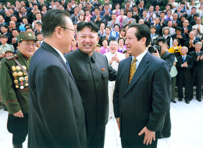 Park Sang-kwon (right), the honorary chairman of Pyeonghwa Motors Corp. is greeted by North Korean leader Kim Jong-un during his recent visit to the communist state.   Yonhap News