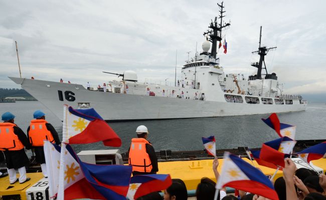 This file photo shows students waving miniature national flags as a Philippine Navy high-endurance Hamilton-class cutter, the BRP Ramon Alcaraz, which had been decomissioned by the U.S. Coast Guard and acquired by Manila, arrives at the former U.S. naval base in Subic Bay, northwest of Manila.   AFP-Yonhap News