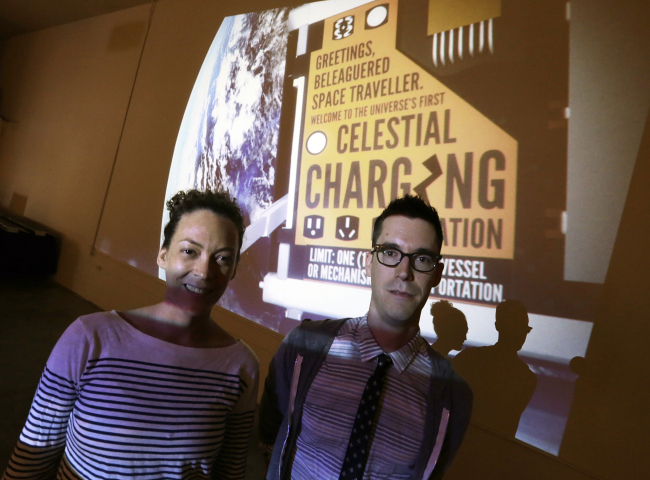 Jon Gibson and Amanda White pose with a projected image of their artwork that will be launched into space, at their studio in the Echo Park district of Los Angeles on July 31.   AP-Yonhap News
