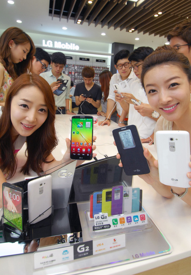 <YONHAP PHOTO-0697> LG G2 전국판매 개시 (서울=연합뉴스) 14일 서울 강남구 청담동 LG베스트샵 강남본점에서 고객들이 'LG G2'를 시연해 보고 있다. LG G2는 후면키(Rear Key)를 적용해 눈으로 버튼을 찾는 번거로움 없이 손가락만으로 전원과 볼륨을 조작할 수 있는 것이 특징이다. 2013.8.14 << LG전자 제공 >> photo@yna.co.kr/2013-08-14 11:39:09/ <저작권자 ⓒ 1980-2013 ㈜연합뉴스. 무단 전재 재배포 금지.>
Models pose with LG Electronics’ newest smartphone the G2.   Yonhap News