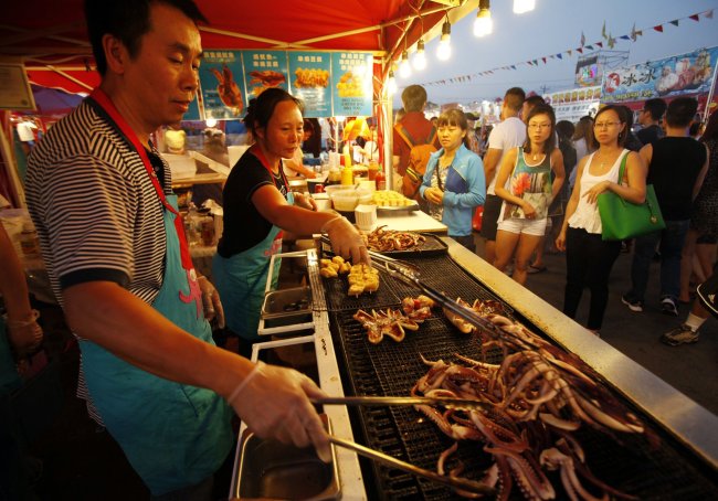 Seng Sivilay (left) and Spina Huang prepare food at their barbecue Squid stand in the Asia market in Richmond near Vancouver, British Columbia, Canada. (MCT)
