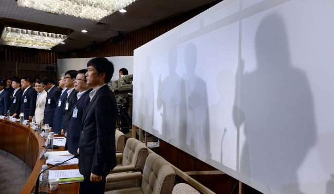 Former and current National Intelligence Service officials (behind the screen) swear an oath at a parliamentary probe into the spy agency’s alleged election interference at the National Assembly on Monday. Park Hyun-koo/The Korea Herald