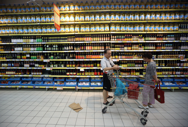 Shoppers browse in front of bottles of oil displayed at a store in Shanghai, China.   Bloomberg