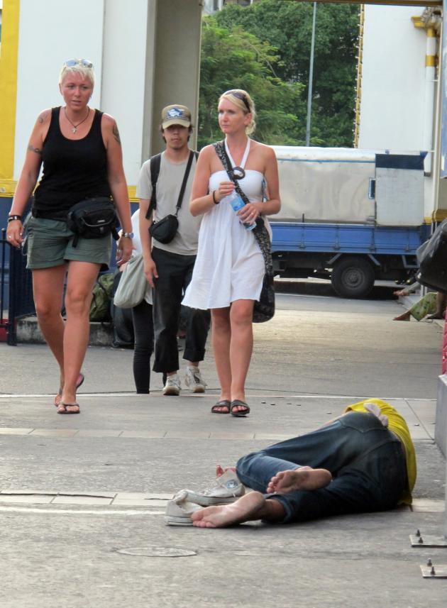 A homeless man lies on the street in Thailand.   The Nation