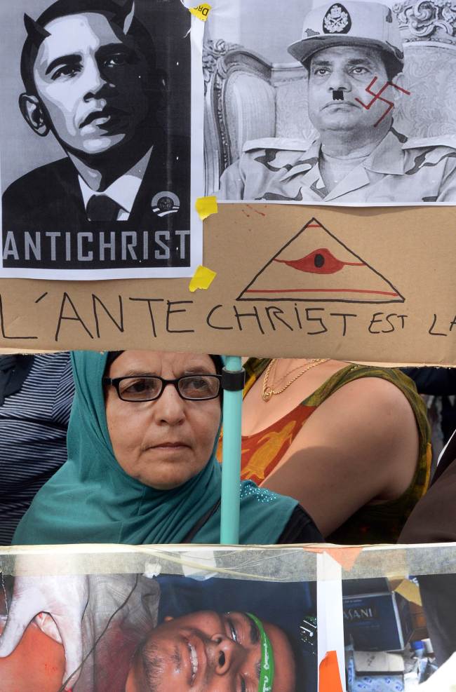 A demonstrator holds a placard depicting U.S. President Barack Obama as the Antichrist and Egyptian Gen. Abdel Fattah al-Sisi as a Nazi, as she takes part in a protest against the Egyptian military’s ouster of President Mohammed Morsi and the recent army-installed government in Paris on Sunday.   AFP-Yonhap News