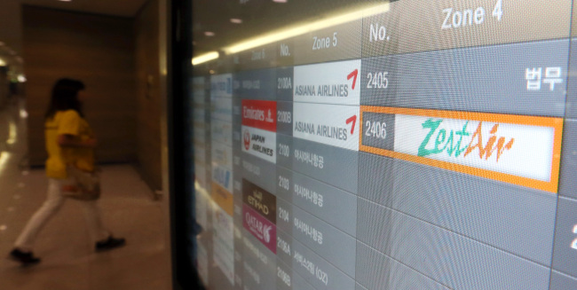 A traveler walks past a sign of Zest Airway, which left passengers stranded in the Philippines after violating safety rules.    Yonhap News