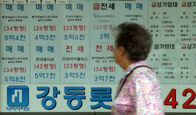 An elderly woman passes by a local real estate agent‘s office in Songpa-gu, Seoul, in this Aug. 4 file photo. (Yonhap News)