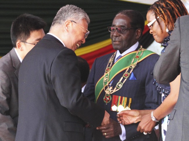 Zimbabwean President Robert Mugabe (third from left) shakes hands with Chinese President Xi Jinping’s special envoy, Minister of Civil Affairs Li Liguo (second from left), after he was sworn in for another five-year term at the National Sports Stadium in Harare on Thursday.   Xinhua-Yonhap News