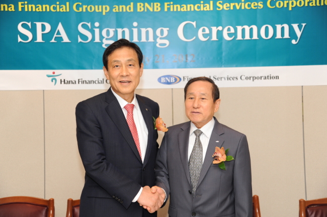 Hana Financial Group chairman Kim Jung-tai (left) poses with BNB Financial Services Corp. head Sam C. Chung after signing a pact to take over the New York-based lender, whose flagship unit is Broadway National Bank, in July 2012.   Hana Financial