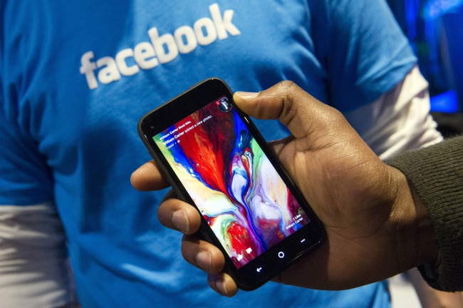 A Facebook Inc. employee holds a phone running the new Home program at the company’s headquarters in Menlo Park, California.    Bloomberg