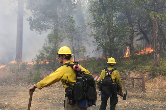 Two firefighters watch trees burn while battling the Rim Fire near Yosemite National Park, California, Monday.   AP-Yonhap News