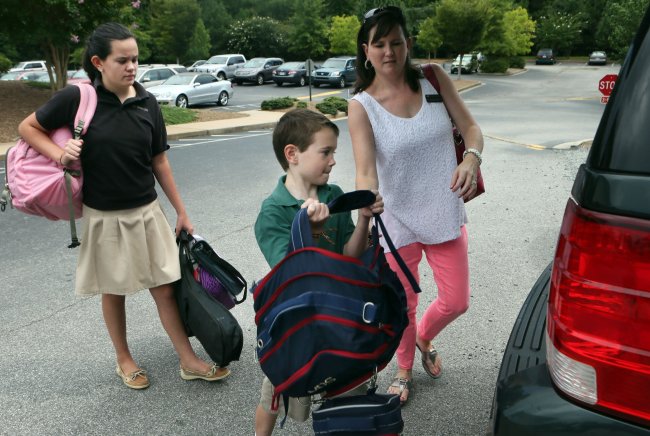 Suzanne Schaefer (right) helps her daughter Maggie (left) and son Matthew load their heavy backpacks and gear into the family car while leaving Cornerstone Preparatory Academy at Summit Baptist Church in Kennesaw, Georgia, Aug. 9.   Atlanta Journal-Constitution/MCT