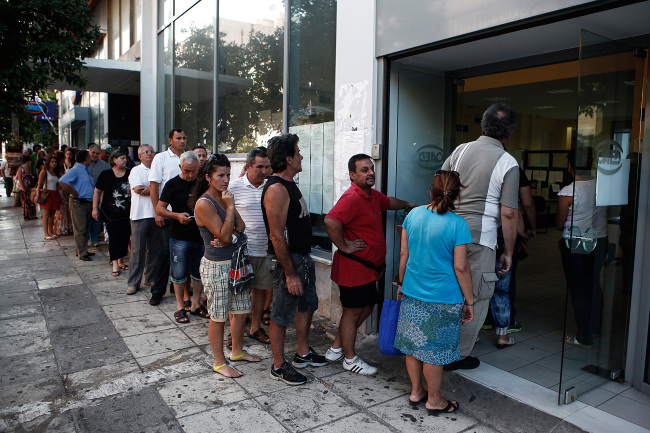 Jobseekers line up to enter a Labor Force Employment Organization job center soon after opening in Athens.   Bloomberg