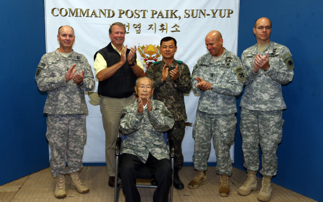 Gen. Paik Sun-yup (seated), 8th Army Deputy Commanding General for Operations Maj. Gen. Walter M. Golden Jr. (left) and others applaud during a ceremony to name Paik the honorary 8th Army commander at the New Mexico Range near Panmunjeom in Gyeonggi Province on Thursday.   Lee Sang-sub/The Korea Herald