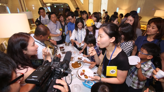 A gaggle of youth crowds a buffet table for a taste of traditional Omani treats during an open house of the Omani Embassy in Seoul on Friday. (Omani Embassy)